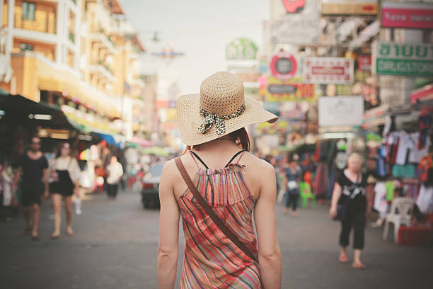 Young woman walking in Khao San, Bangkok Rear view of a young woman walking the famous backpacker street Khao San in Bangkok, Thailand khao san road stock pictures, royalty-free photos & images