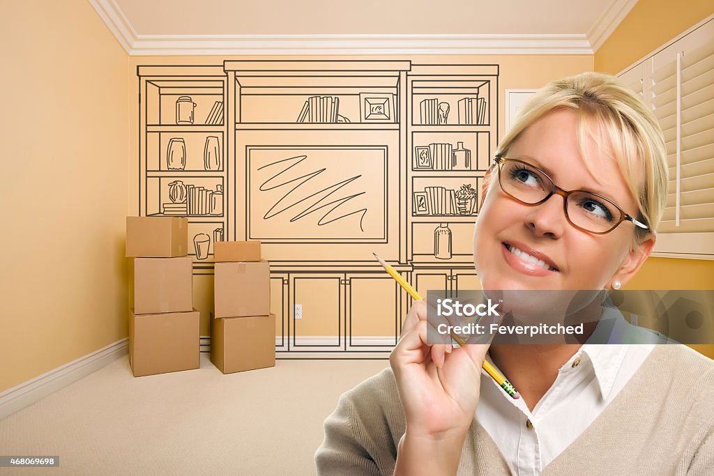 Daydreaming Woman Holding Pencil In Room with Shelf Drawing Daydreaming Woman Holding Pencil In Empty Rom with Built In Shelf Design Drawing on Wall. 2015 Stock Photo