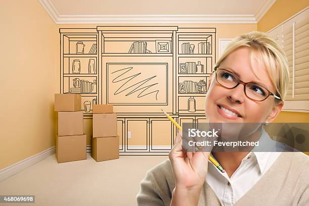 Daydreaming Woman Holding Pencil In Room With Shelf Drawing Stock Photo - Download Image Now