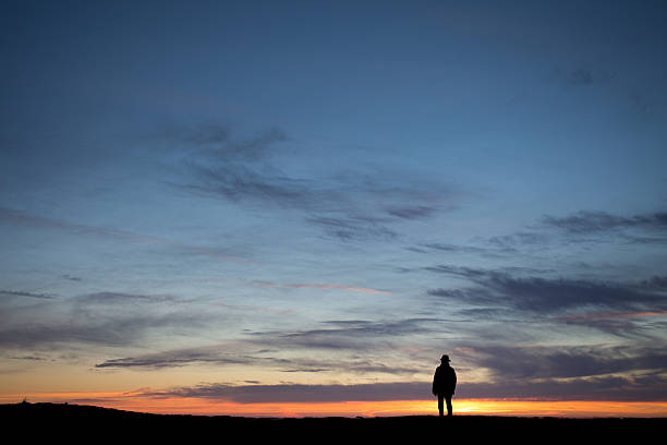 istock silhouetted elderly man standing in front of a sunset sky 468079918