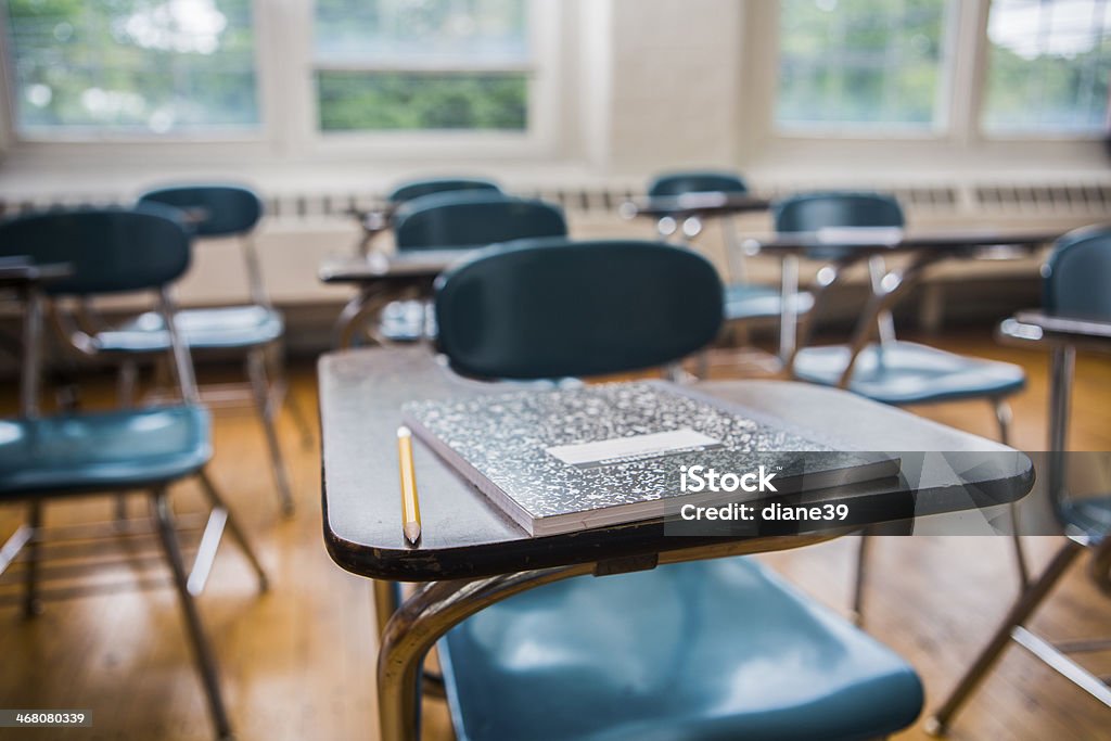 School desks in a Classroom A notebook and pencil on a desk in a school classroom Classroom Stock Photo