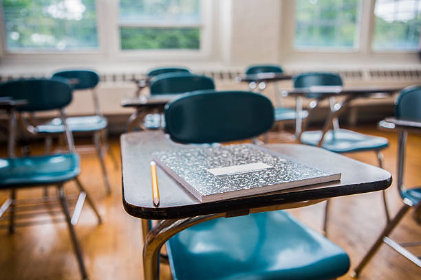 School desks in a Classroom A notebook and pencil on a desk in a school classroom school supplies photos stock pictures, royalty-free photos & images
