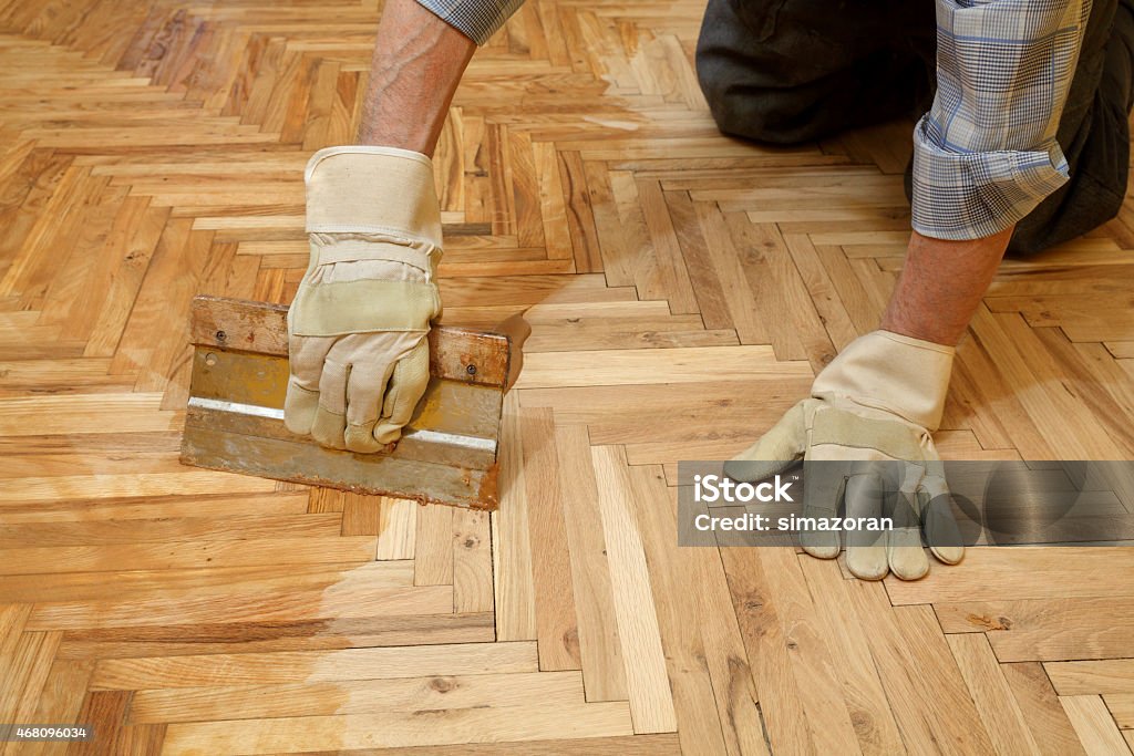 Home renovation, parquet finishing Varnishing of oak parquet floor, workers hand and tool Parquet Floor Stock Photo