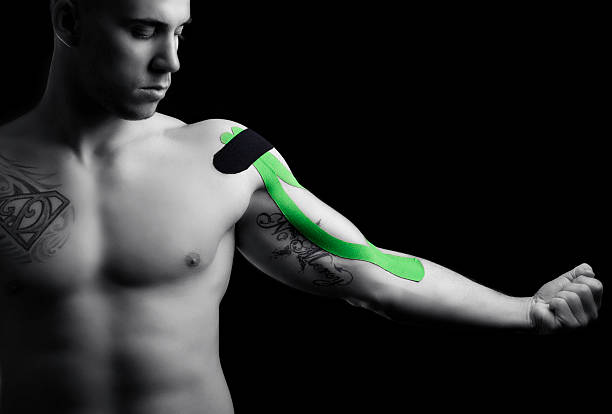 молодой спортсмен с kinesiotape на его бицепс - muscular build men tattoo human arm стоковые фото и изображения