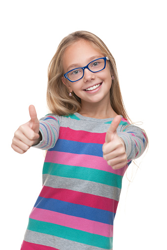 A preteen girl in a glasses holds her thumbs up against the white background