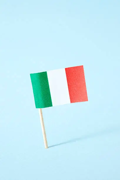 Paper italian flag over blue background