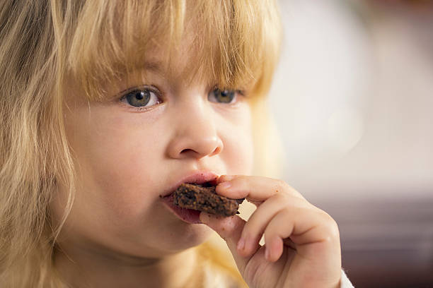 istock Little Girl Eating Chocolate Chip Cookie 468111924