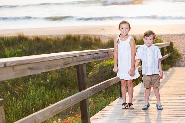 duas crianças em pé na praia boardwalk - beach family boardwalk footpath - fotografias e filmes do acervo