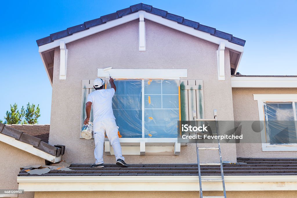 House Painter Painting the Trim And Shutters of Home Busy House Painter Painting the Trim And Shutters of A Home. Painting - Activity Stock Photo