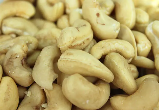 Close-up photo showing some kidney-shaped cashew nuts, which are shown shelled and piled high.  Cashews are considered to be a very healthy snack food that can be eaten between meals, while these nuts are often also used as an ingredient in salads and Chinese-style chicken stir fries, due to their sweet flavour.