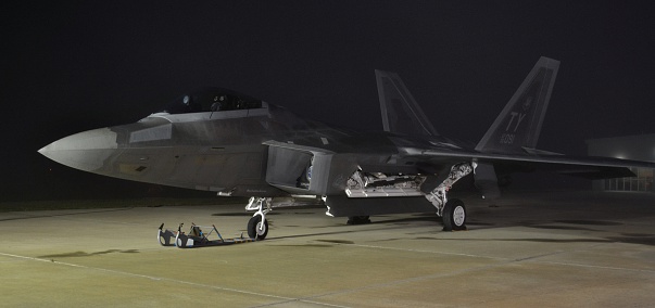Melbourne, USA - March 21, 2015: An Air Force F-22 Raptor stealth jet sits on a flight line at night. This F-22 is part of the 325th Fighter Wing, stationed at Tyndall Air Force Base. 