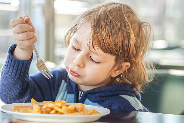 istock boy eating french fries 468132298