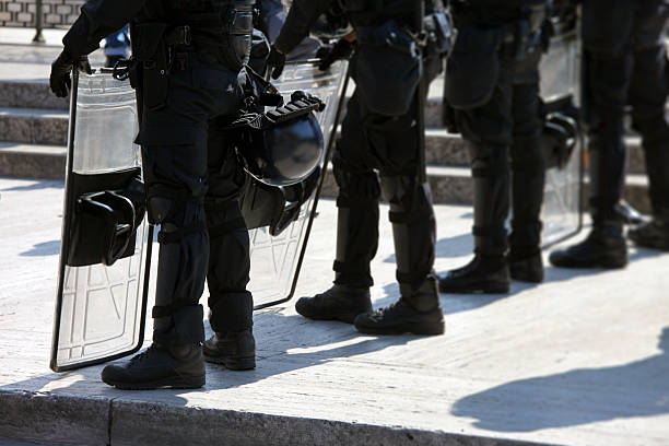 Low section shot of unrecognizable riot policemen with shields standing on street during parade on National Anniversary of Greece