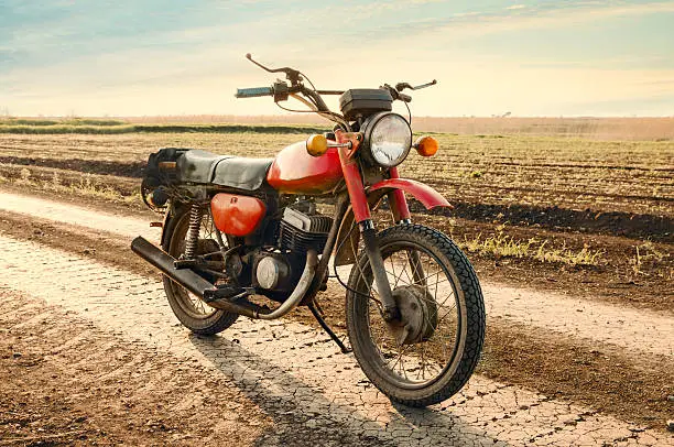 Photo of Classic old motorcycle on a dirt road.