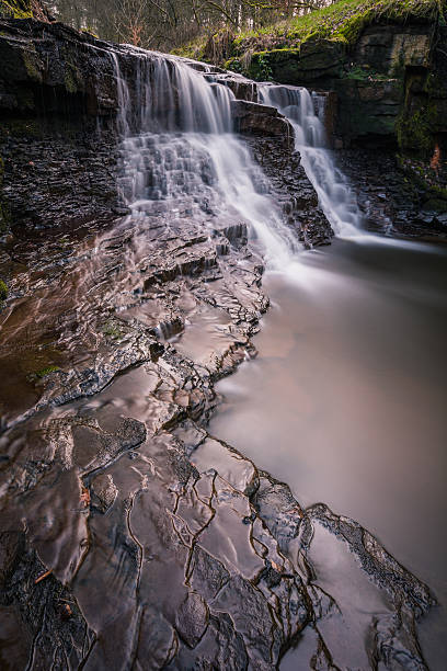 istock Stunning Waterfall With Textured Rocks In Foreground. 468135790