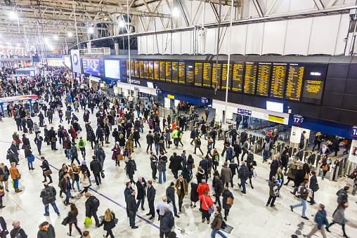 London, United Kingdom - March 18, 2015: Commuters and tourists in the hall of Waterloo train station during peak hours. Some of them are looking at time tables some others are walking in all directions.