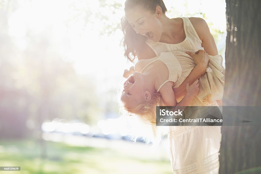 happy mother and baby having fun near tree Happy mother and baby having fun near tree Adult Stock Photo