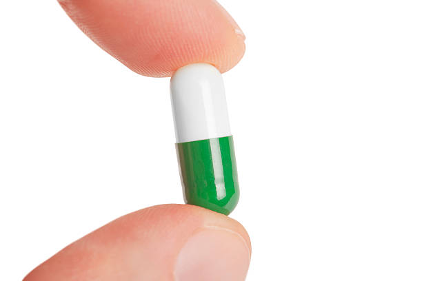 istock fingers hold the capsule pills 468148116
