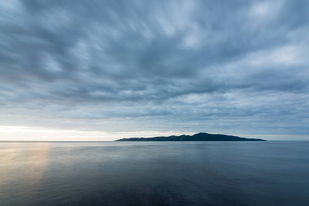 Looking north west to Kapiti Island from Raumati Beach on a cloudy evening.