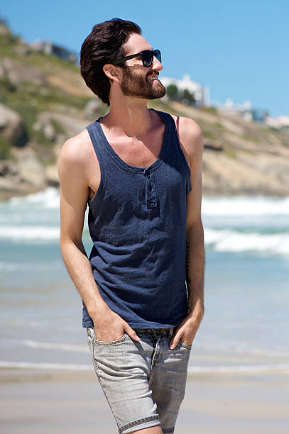 istock Smiling man walking on the beach with sunglasses 468150366