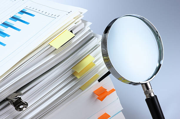 Investigate and analyze. Magnifying glass and stack of documents. analyzing document stock pictures, royalty-free photos & images