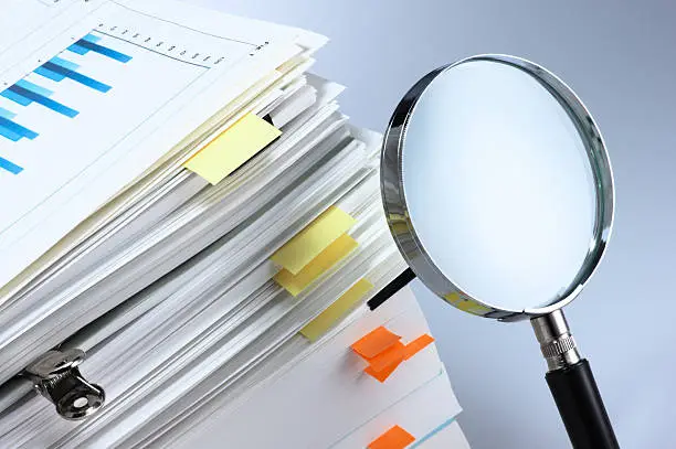Magnifying glass and stack of documents.