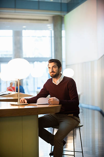 istock Businessman with file at table in lobby at office 468157040
