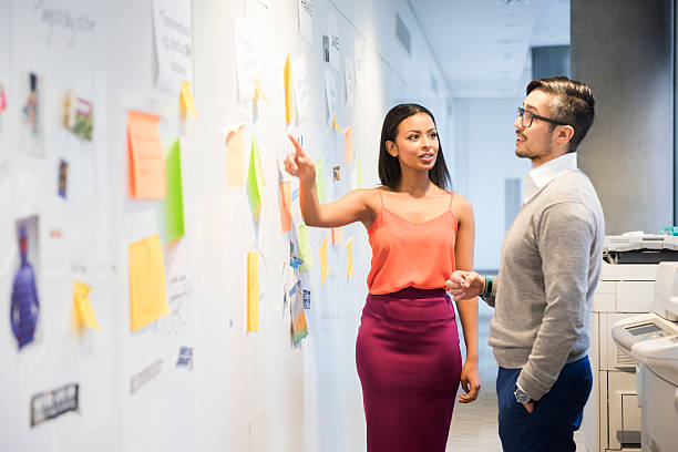 istock Business people discussing over notes stuck on wall. 468158048