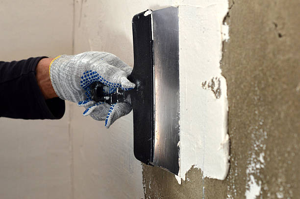istock process of applying a white putty on concrete gray wall 468162380