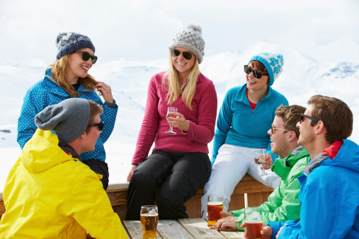 Group Of Friends Enjoying Drink In Bar At Ski Resort Smiling And Laughing.