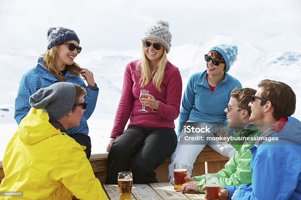 Group Of Friends Enjoying Drink In Bar At Ski Resort Group Of Friends Enjoying Drink In Bar At Ski Resort Smiling And Laughing. Apres-Ski Stock Photo