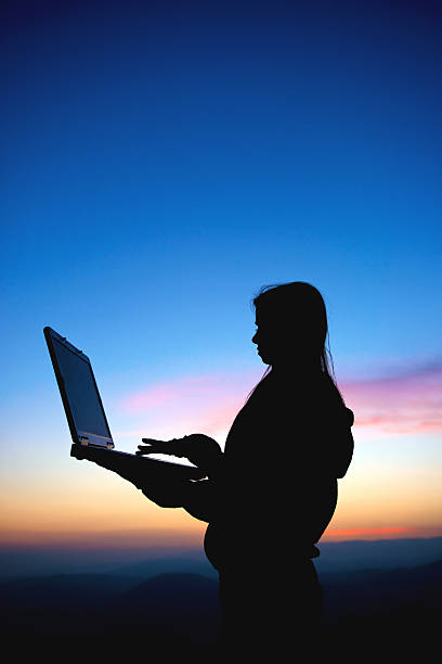istock Girl working with laptop at sunset 468170451