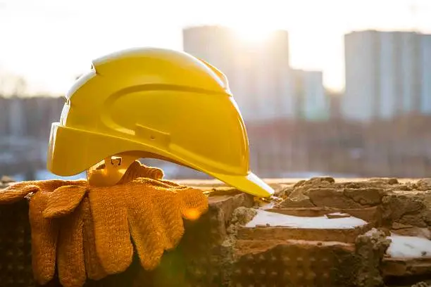 Construction site orange objects on snowy windowsill on new sunset buildings background