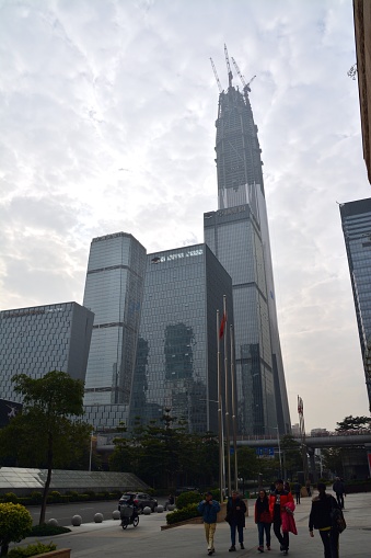Shenzhen, China - February 1, 2015: People walking in Futian business district, Shenzhen. In the background the Ping An International Finance Centre, a megatall skyscraper under construction in Shenzhen. It is expected to be completed in 2016 and will be the 2nd building in the world, as well as the tallest in China at an height of 660 metres .