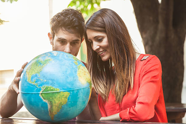 istock Young couple looking at globe together 468187168