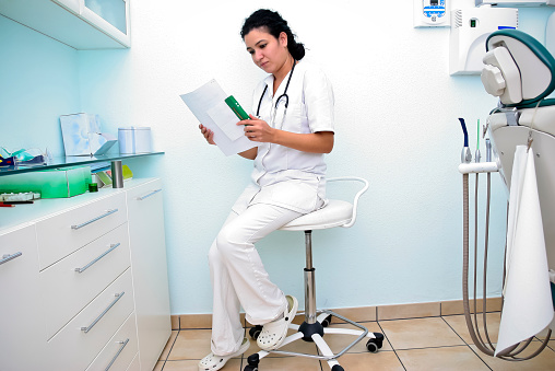 Cheerful female doctor standing in clinic. Portrait of friendly smiling woman physician. Perfect medical service in hospital. Medicine concept.