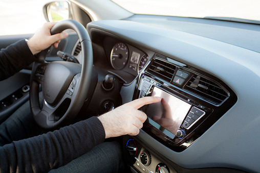 man touching the multimedia touchscreen panel inside a car