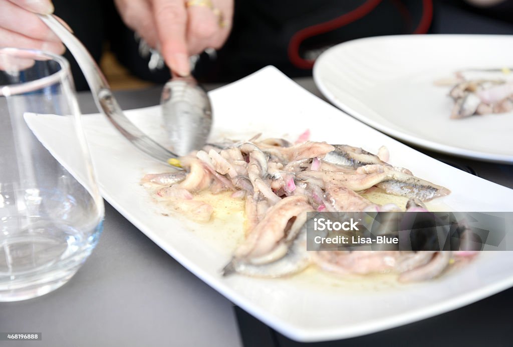 Seafood Woman eating anchovyes with onions in a restaurant. 2015 Stock Photo