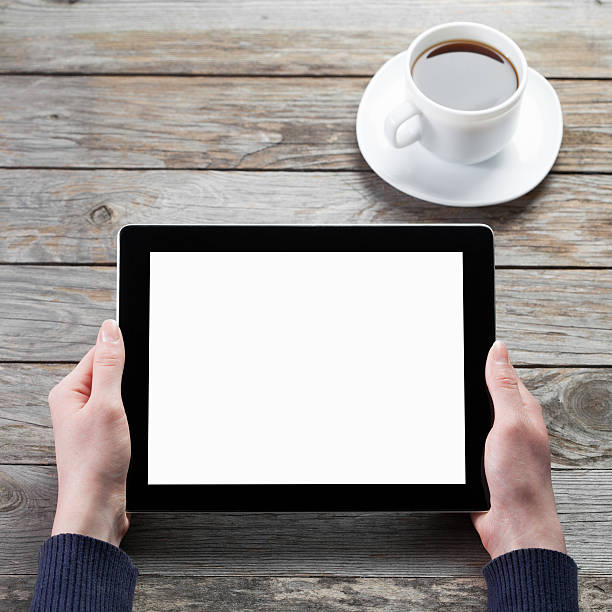 istock Hands holding tablet over a wooden table with coffee cup 468199782