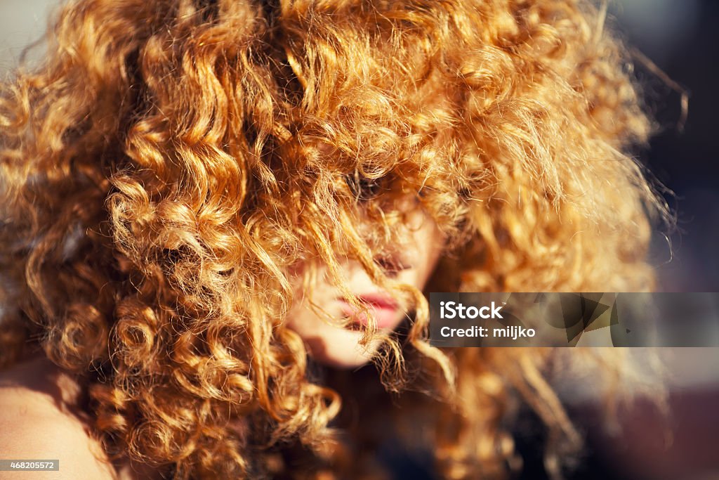 Beautiful redhead woman outdoors Close up shot of woman's beautiful curly red hair. Focus is on the hair in the foreground. Photo taken under the natural daylight 2015 Stock Photo