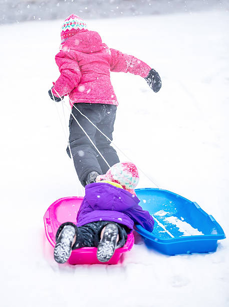istock Girl Pulling Sister Up Hill In Sled 468205616