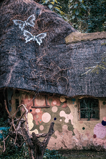 A fairy tale thatched cottage in the woods, painted in spots.