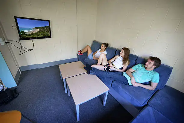 Photo of Three students in a dorm on a couch watching tv