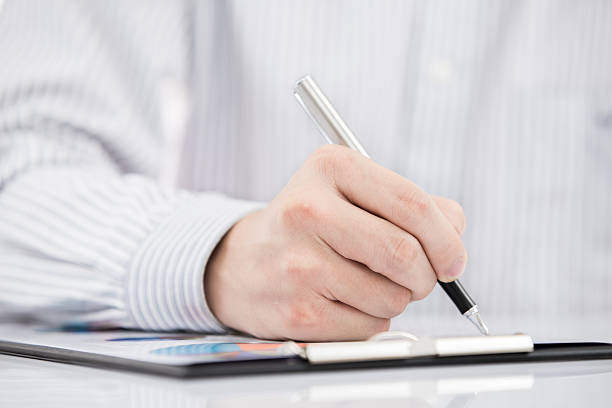 istock man hand with pen and business report 468217031