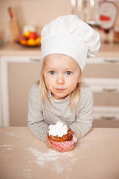 istock Little cute girl with chef hat holding cake 468222940