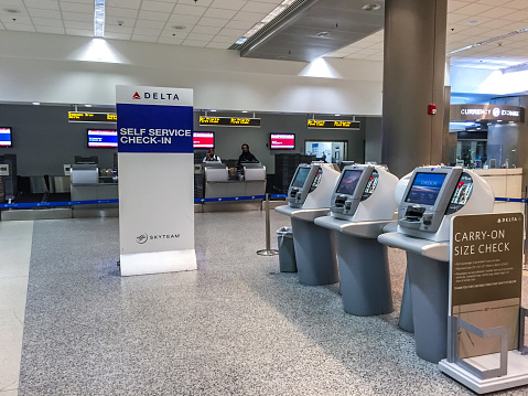 Miami, USA  - January 30, 2015: Miami Airport Self Service check-in. Check-in attendant visible on background