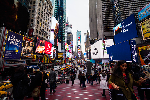 New York City, NY, USA - December 4, 2014: View of Times Square, NYC. Pedestrians and tourists on street and red staircase. Theater and other billboards visible include Cabaret, McDonalds,and Google Android.