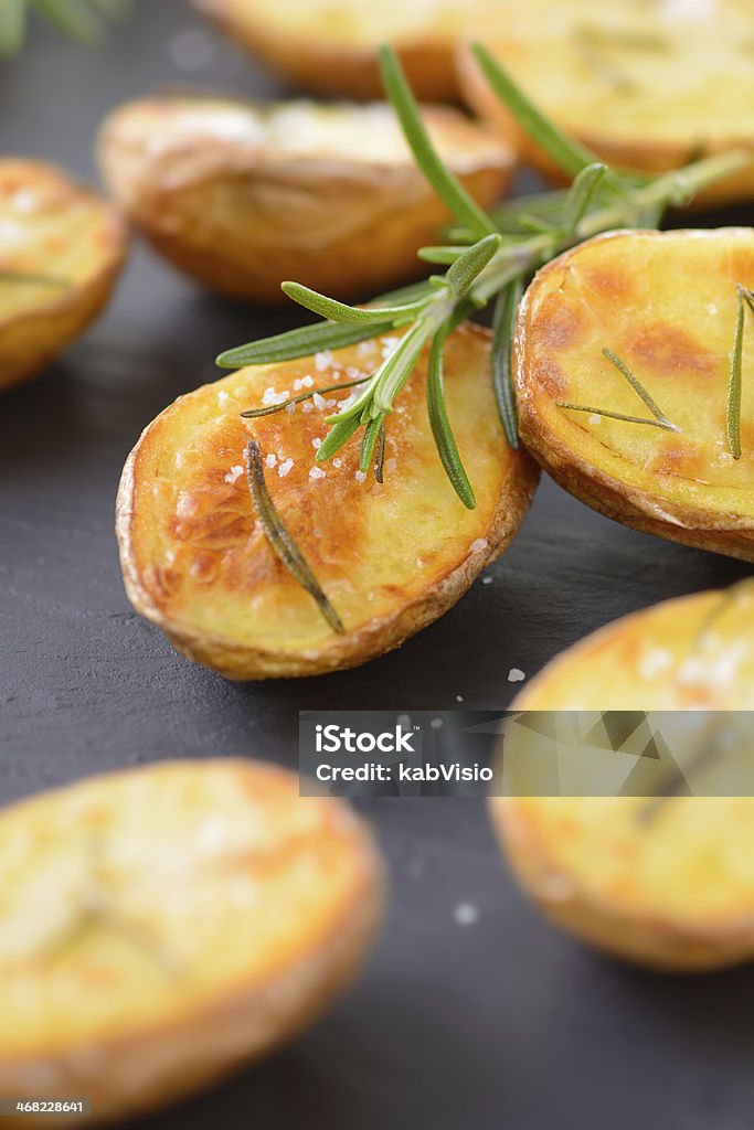 Baked potatoes Baked unpeeled potatoes with rosemary and salt on a slate Baked Stock Photo