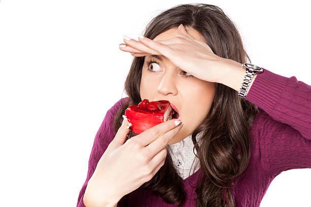 woman eating cake secretly beautiful young woman eating cake secretly tasting cherry eating human face stock pictures, royalty-free photos & images