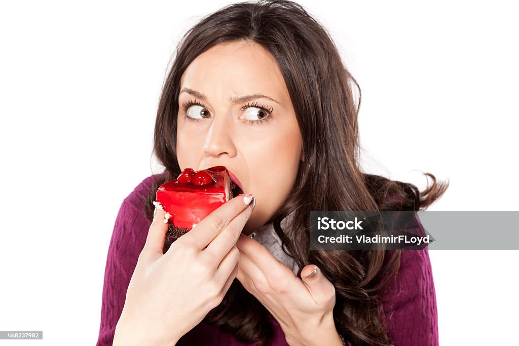 A woman eating a strawberry cake looking guilty beautiful young woman eating cake secretly Eating Stock Photo